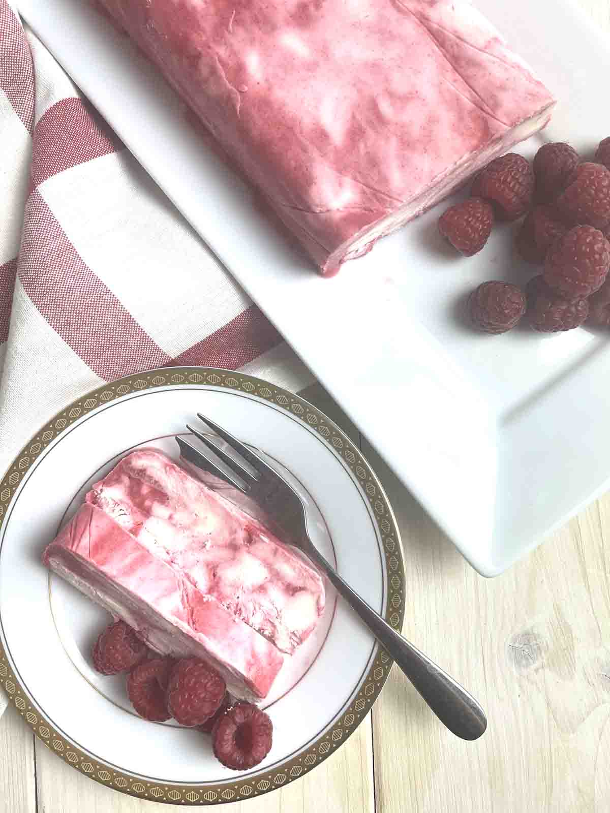 slices of no churn raspberry ice cream on a plate with dessert in the background.