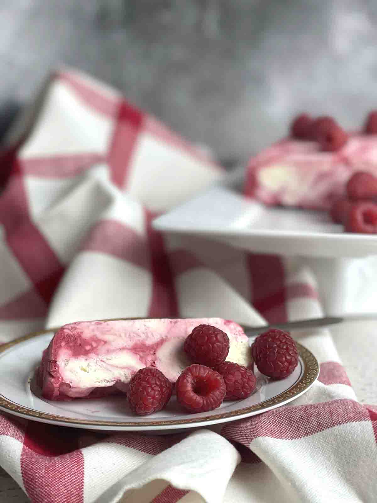 slices of raspberry parfait on a plate with dessert in the background.