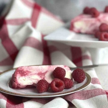 slices of raspberry parfait on a plate with dessert in the background.
