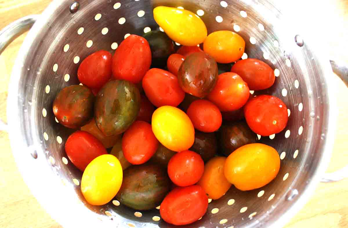 different coloured cherry tomatoes in a colander.