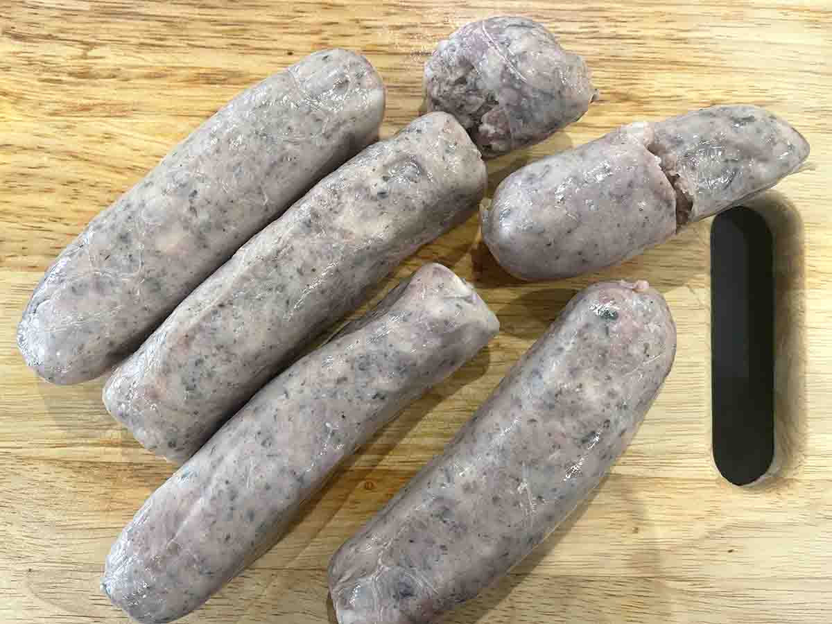 raw Lincolnshire sausages on a board.
