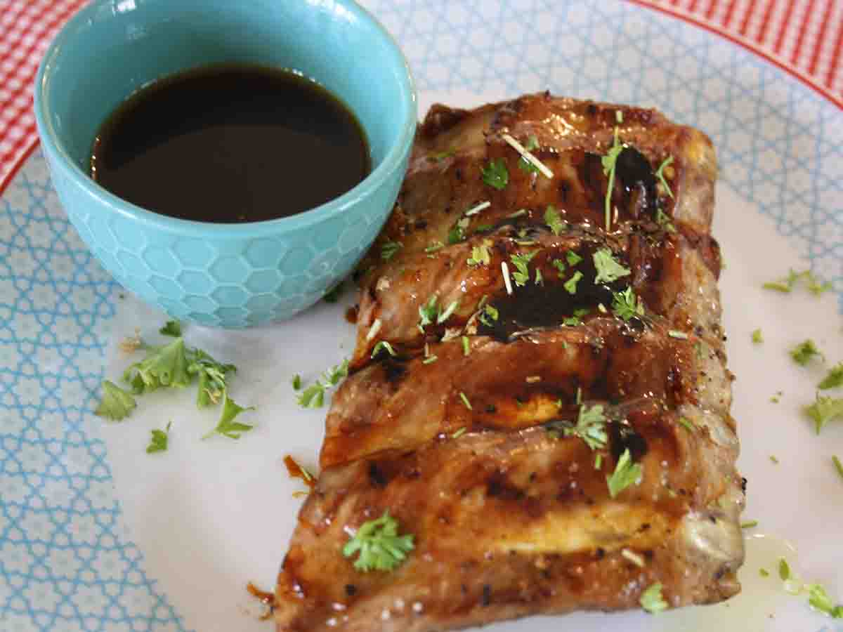 cooked ribs with pot of sauce.