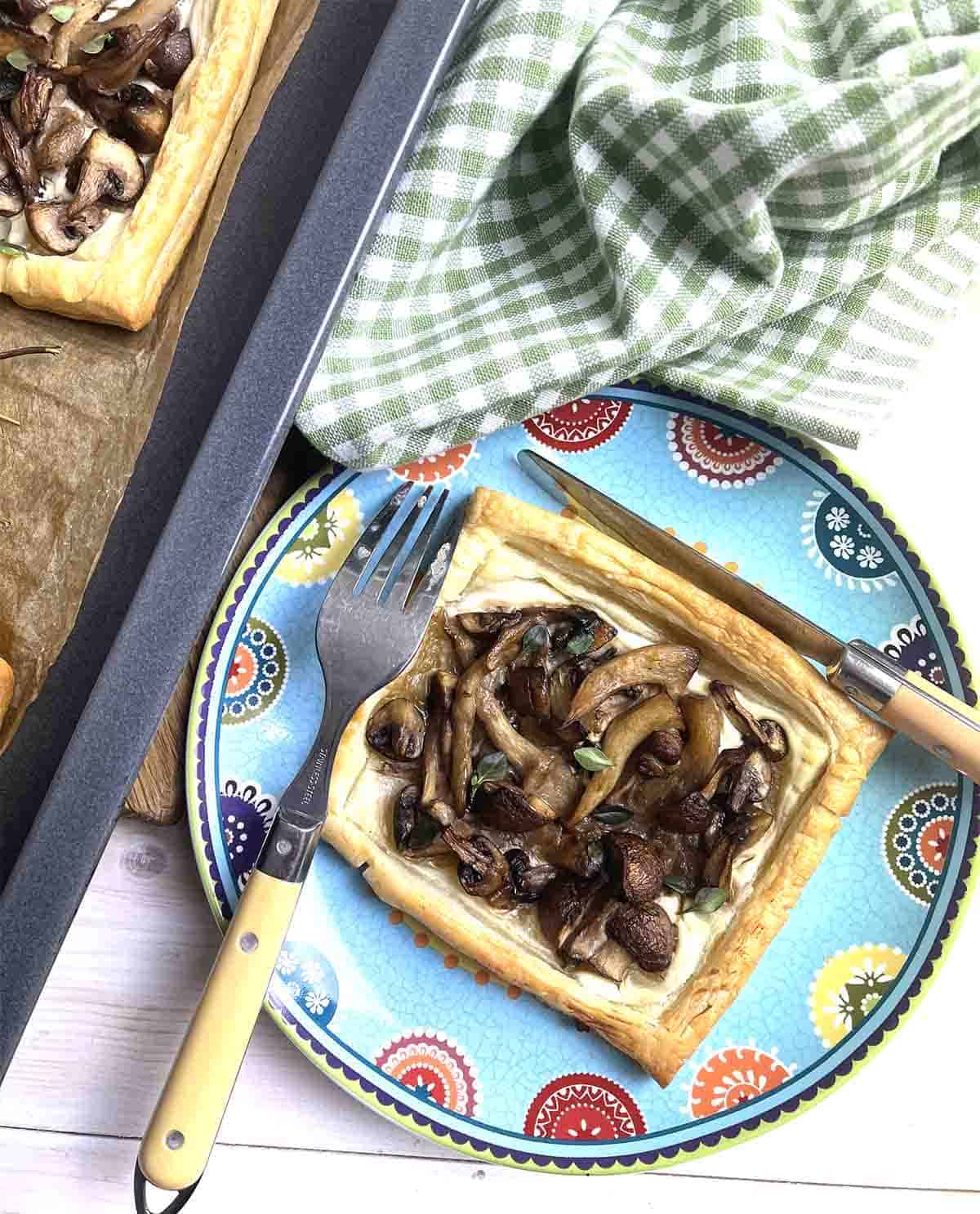Vegetarian mushroom tart on a plate with cutlery.