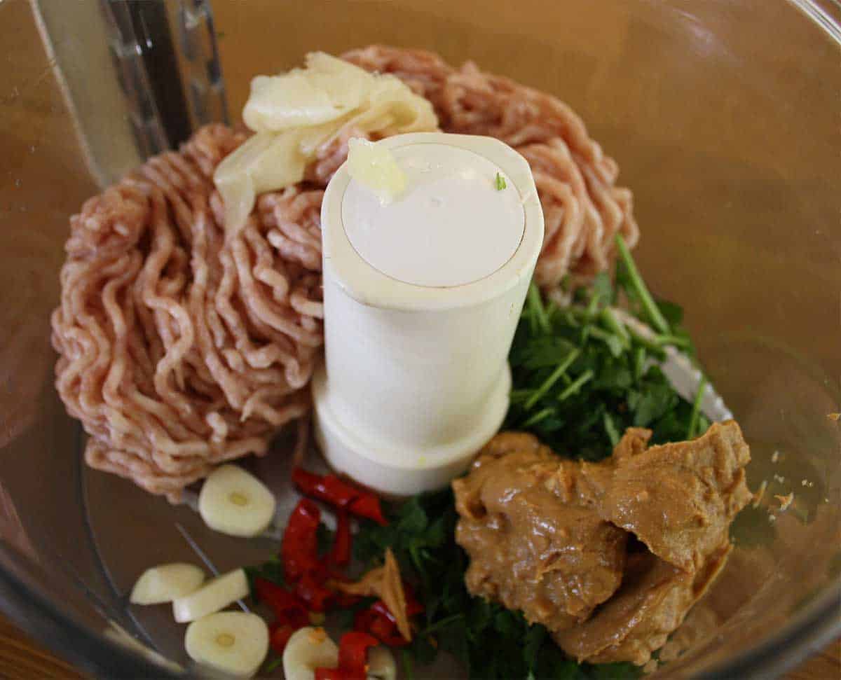 pork mince, garlic, chillies and other ingredients in a food processor bowl.