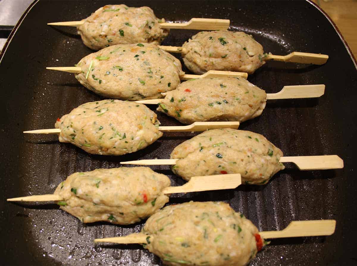 pork mince on a stick ready to cook in a pan.