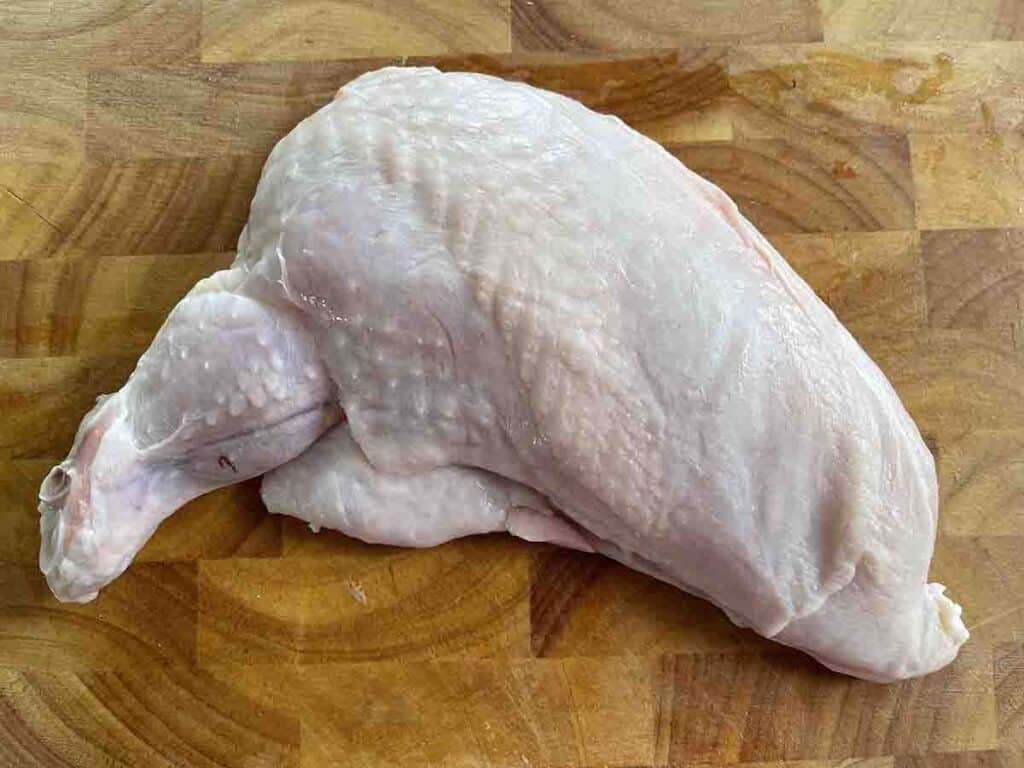 boneless chicken breast supreme on a chopping board.