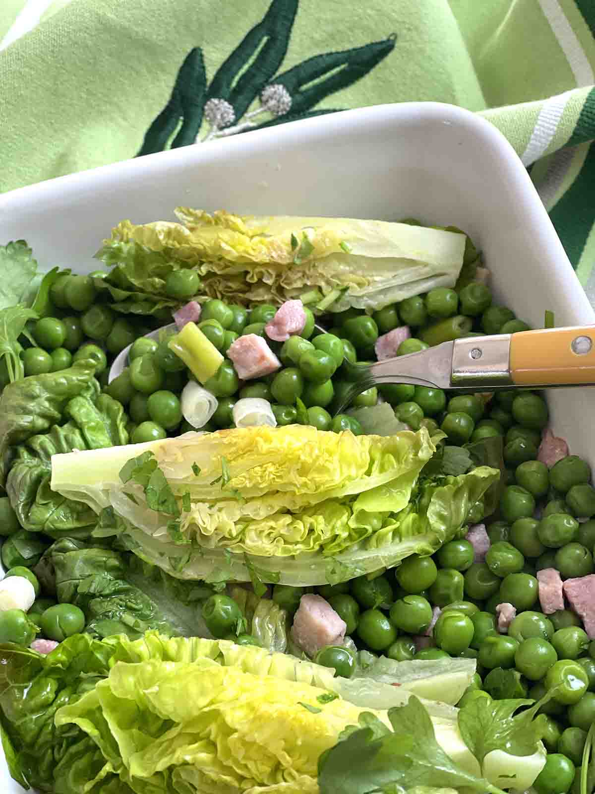 cooked peas in a serving dish with a spoon.