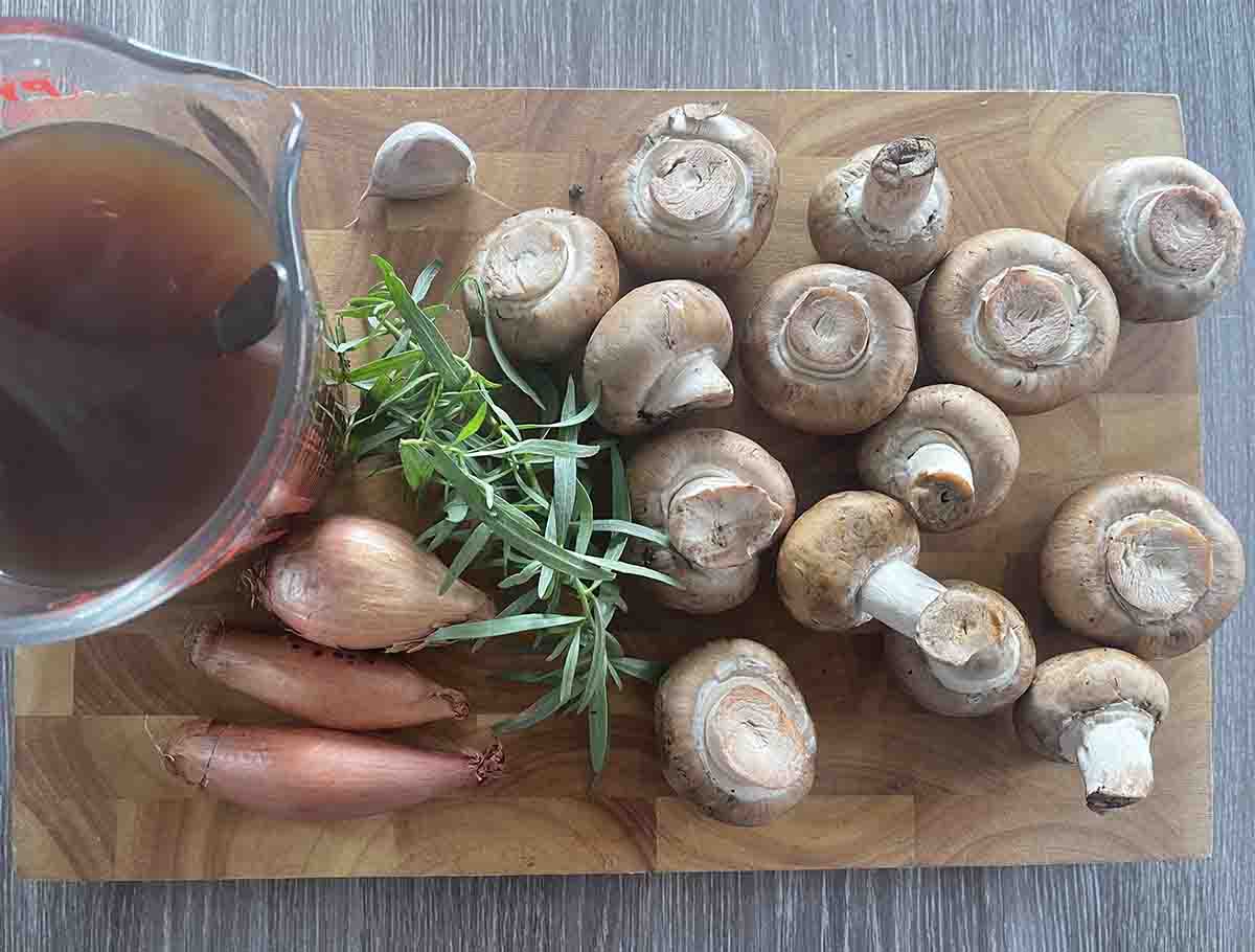 mushroomsm shallots, tarragon and stock on a board.