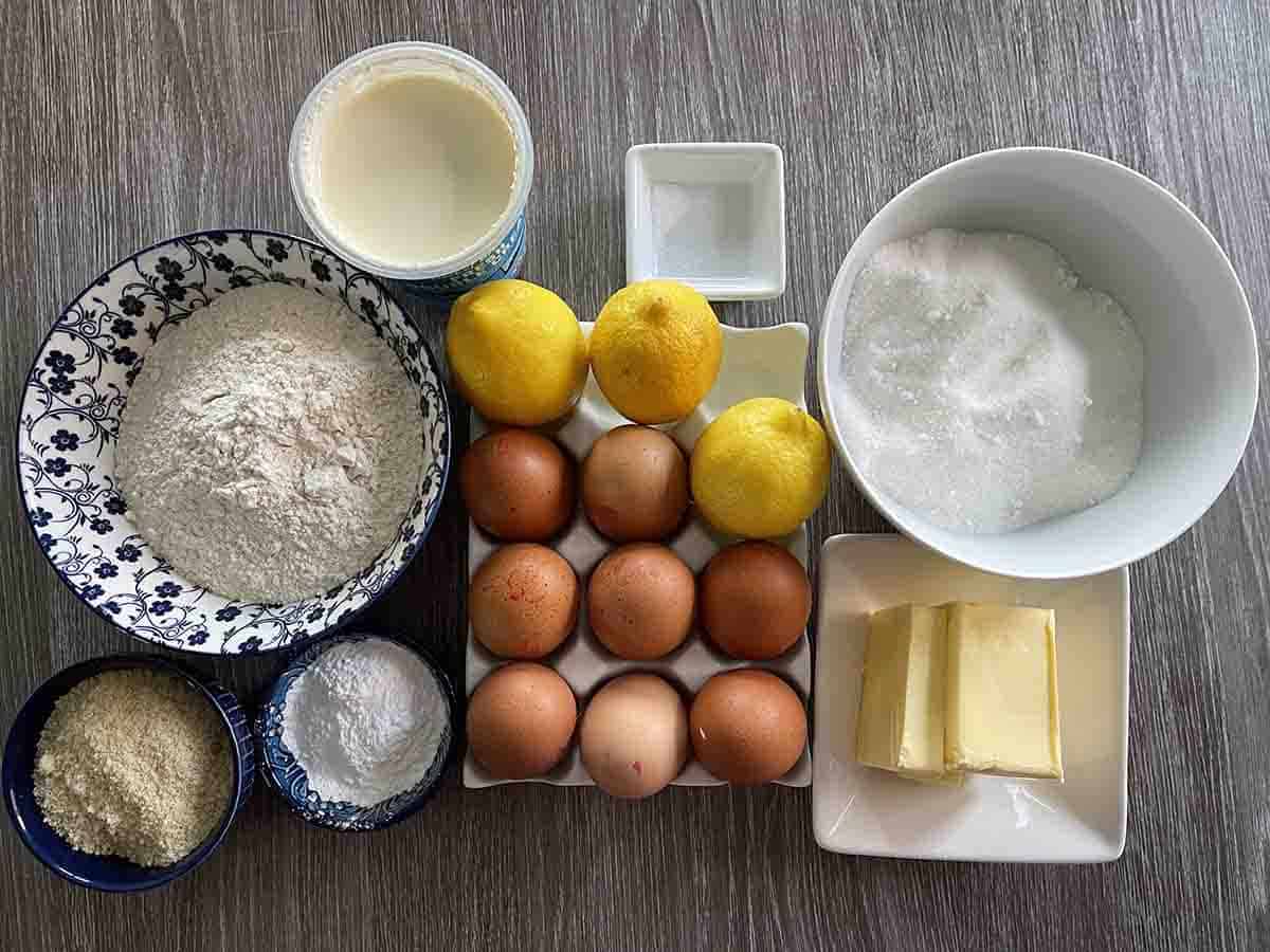 ingredients for tart including eggs, lemons, sugar, flour, icing suage, ground almonds, butter and cream.