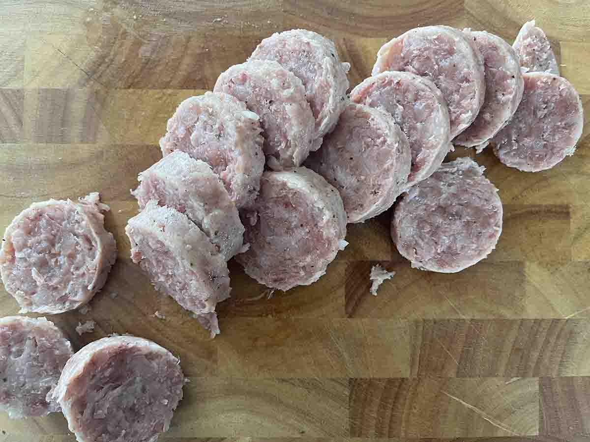 cooked sausage sliced on a board.