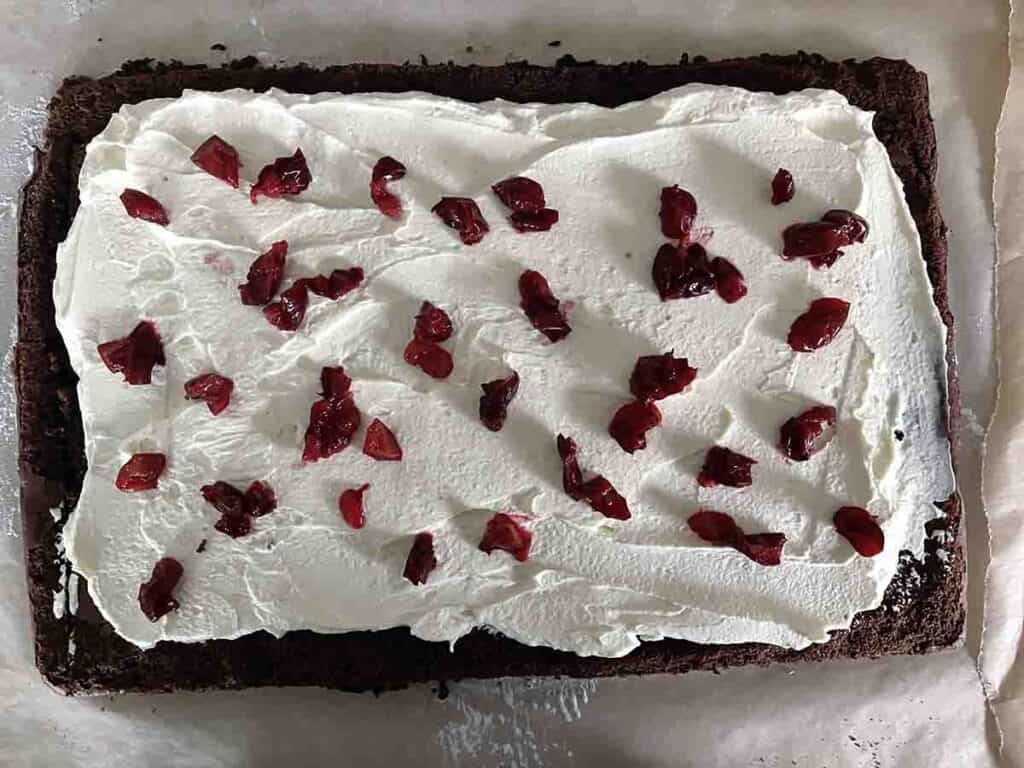 sponge spread with cream and topped with chopped cherries.
