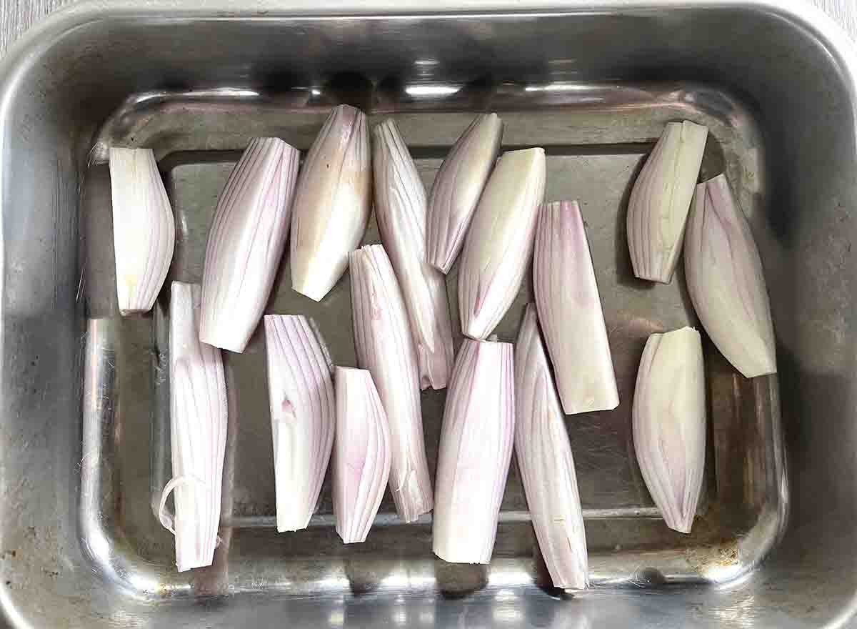 quartered shallots in a roasting tray.