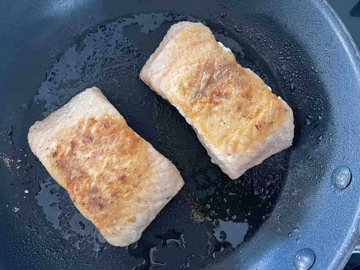 salmon frying in a pan.