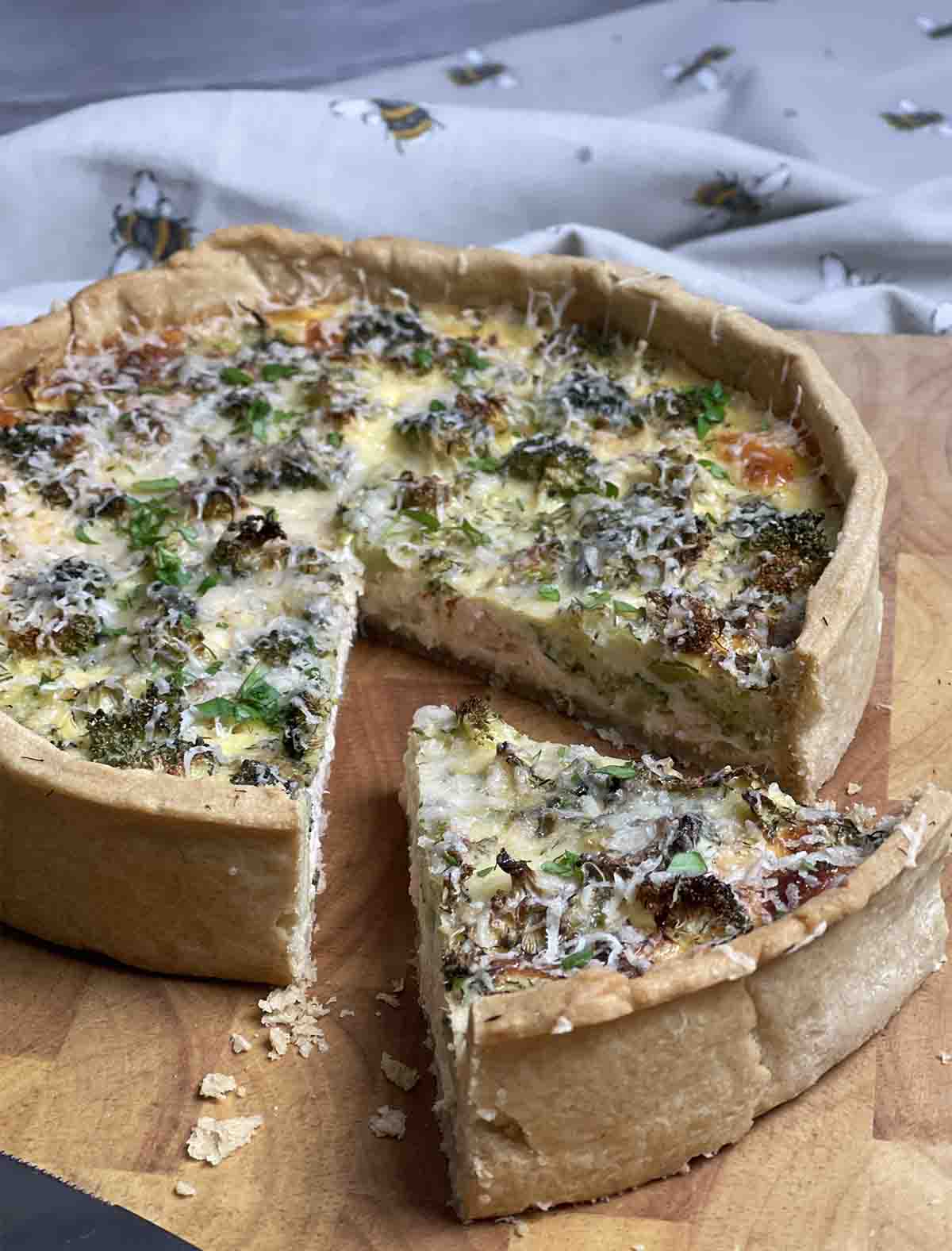 quiche on a board with a slice cut out.