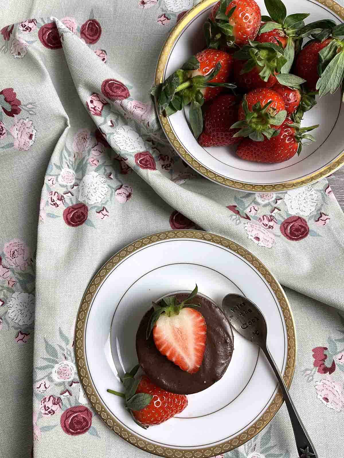 chocolate dessert on a plate with strawberries in the background.