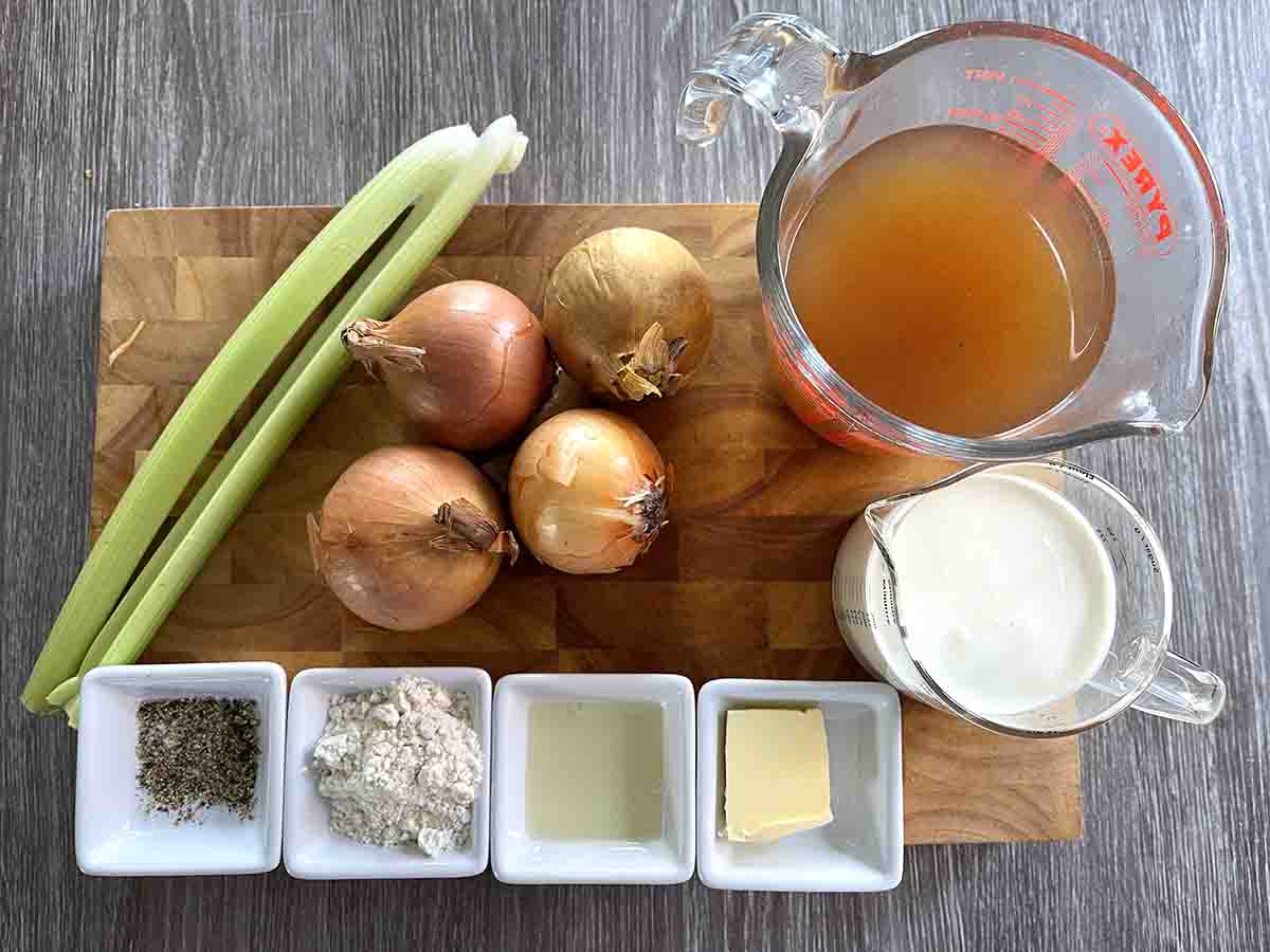 ingredients on a board including onions, stock, celery, cream, oil, butter and seasoning.