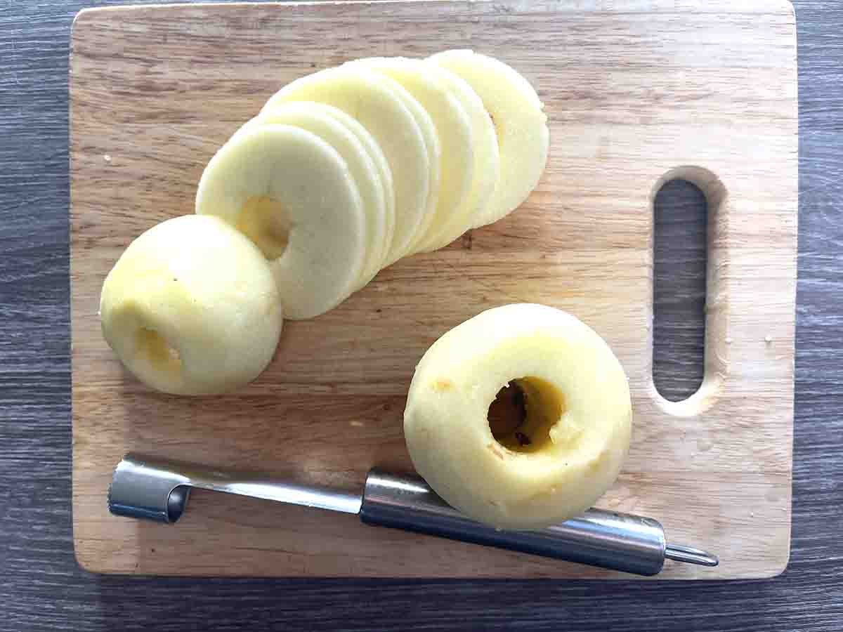 cored and sliced apple on a board.