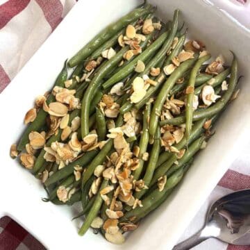 green beans almondine in a white dish.