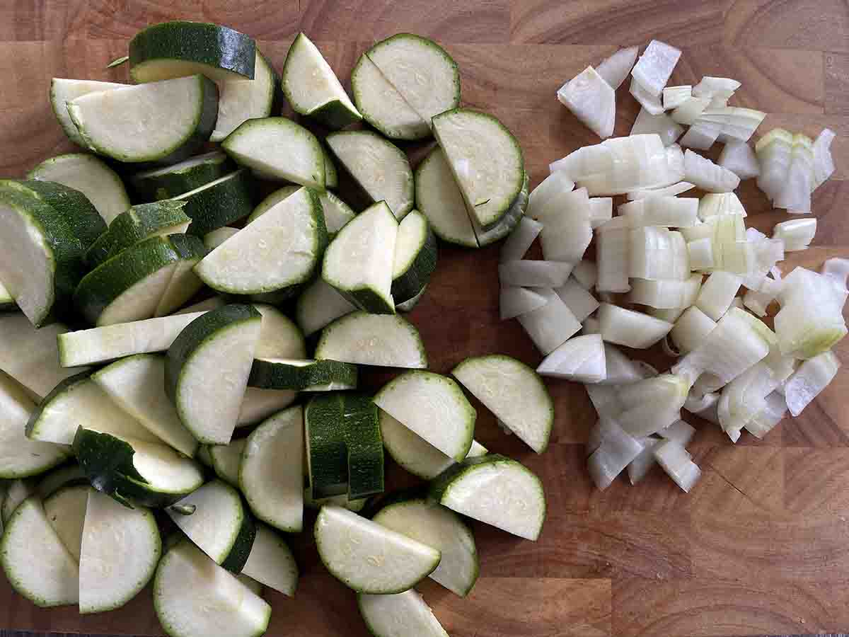 sliced courgettes and chopped onions on a board.