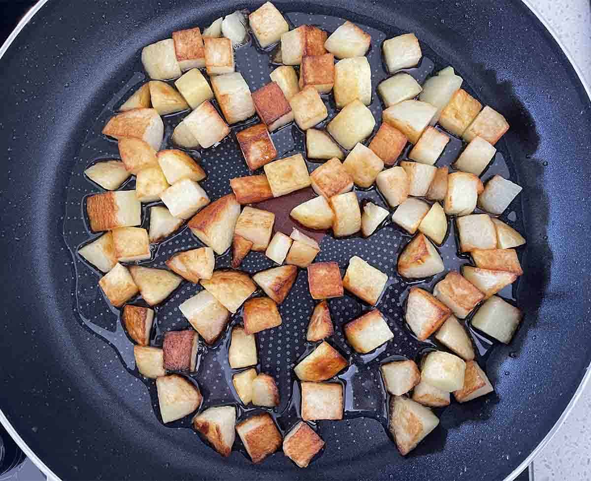 fried cubed potatoes in a pan.