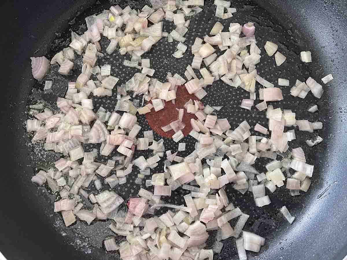 chopped shallots cooking in a pan.