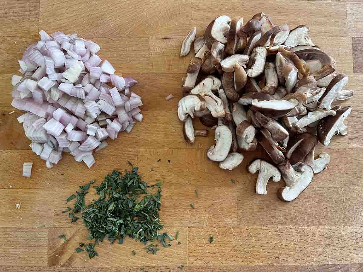 chopped mushrooms, shallots and taragon on a board.