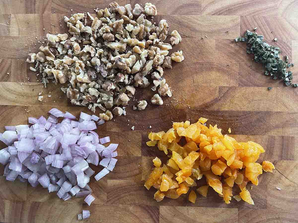 chopped shallots, walnuts, sage and apricots on a board.