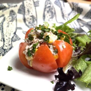 tuna stuffed tomato on a plate with salad.