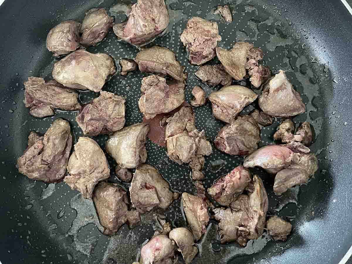 chicken livers cooking in a pan.