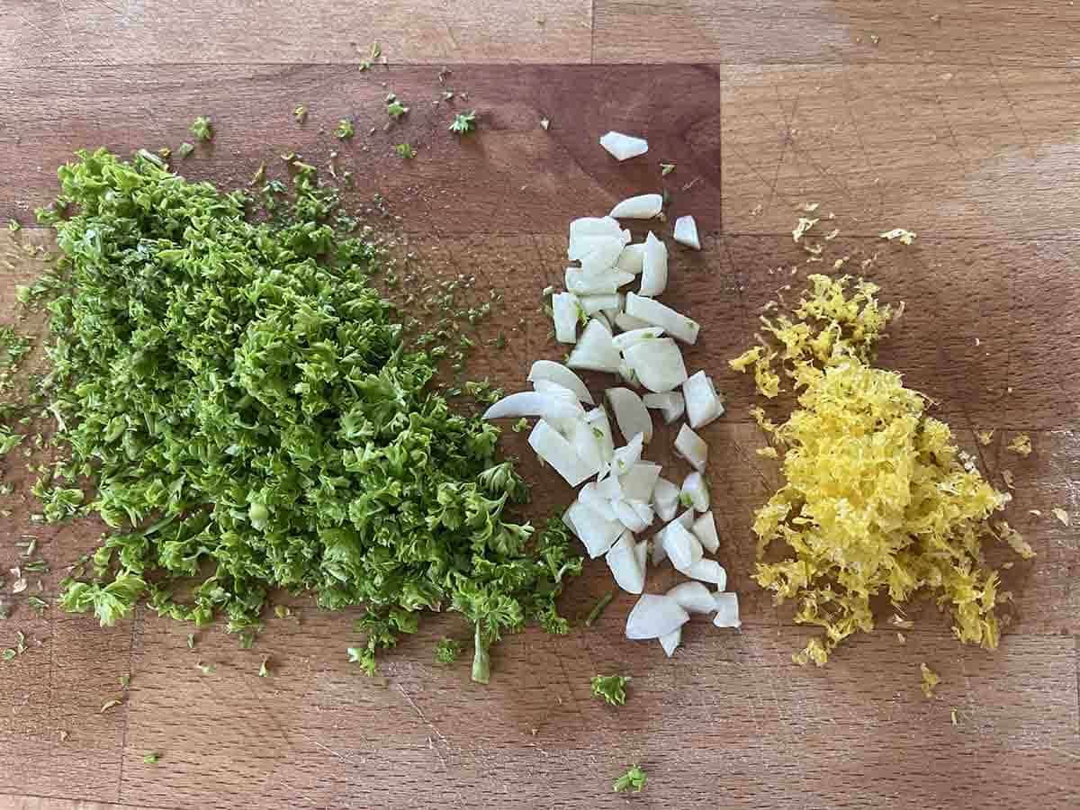 lemon zest, chopped garlic and parsley on a board.