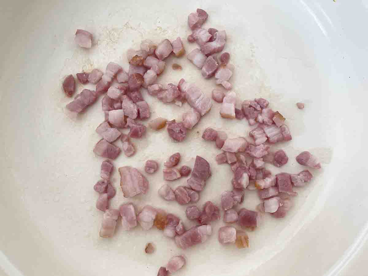 bacon lardons frying in a pan.
